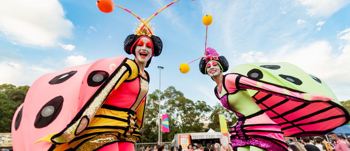 Two stilt walkers dressed as colourful lady bugs at Knox Festival
