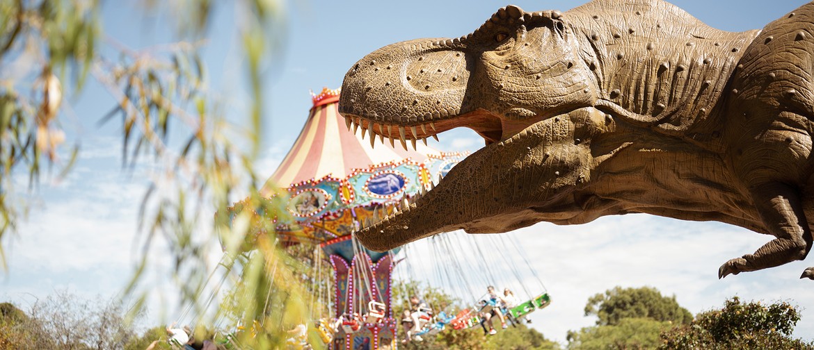 Jurassic Kingdom An animatronic dinosaur is roaring in front of a carnival ride.