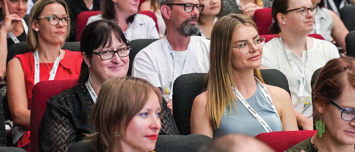 CHANGE 2025 Conference People sitting in the audience at CHANGE conference. One lady is looking at the camera while others around her are looking to the front.