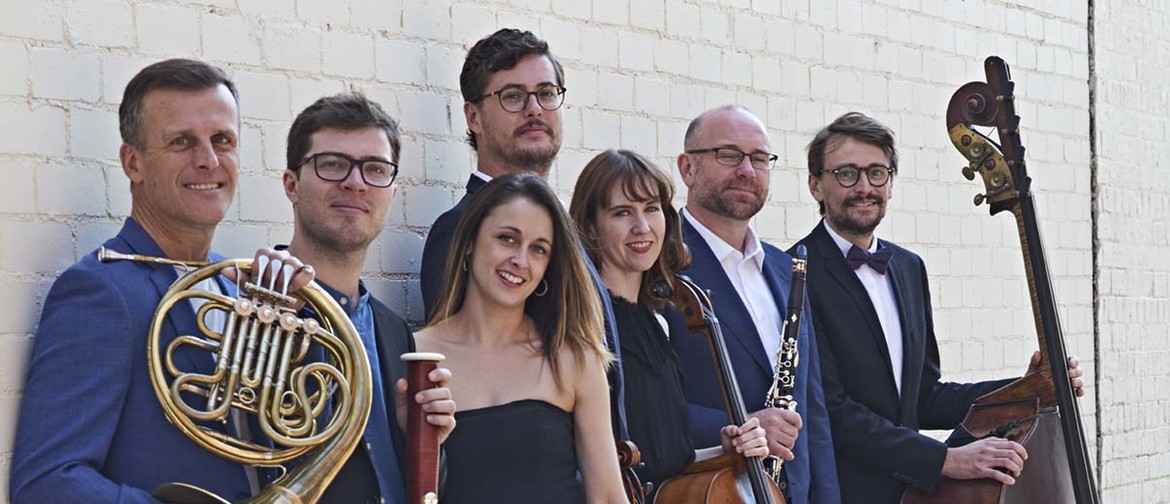 Melbourne Ensemble: Lux Aeterna The Melbourne Ensemble stand with a off-white brick wall in the background, holding their classical instruments and smiling