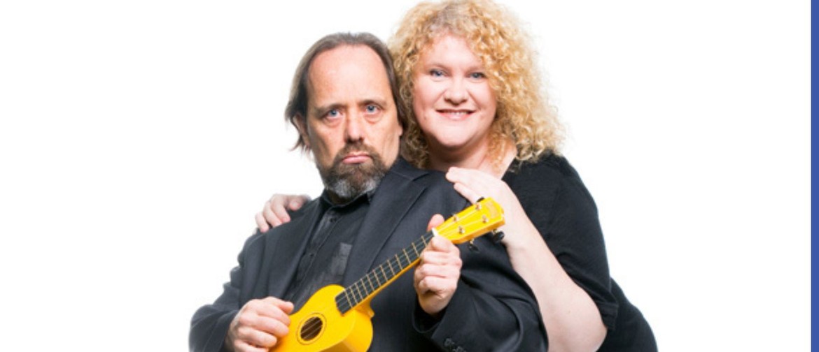 man with a goatie playing yellow ukulele with women with blonde curly hair standing behind with arms on shoulders